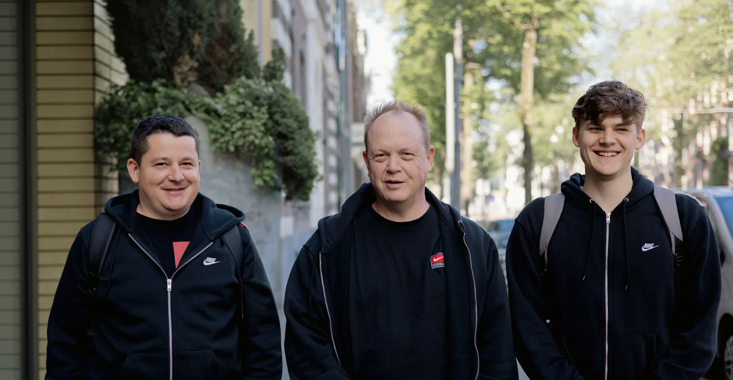 The three people who make Ubikron, on a street lined with trees